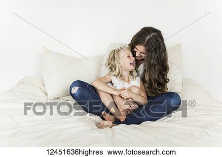 Portrait of a mother and young daughter sitting on a bed spending time together and laughing; Sorrento, British Columbia, Canada View Large Photo Image Stock Photograph - Portrait of a mother and young daughter sitting on a bed spending time together and laughing; Sorrento, British Columbia, Canada. Fotosearch