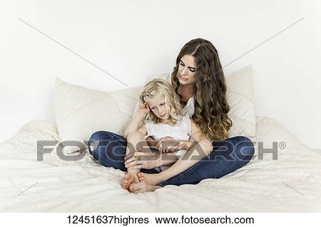 Portrait of a mother and young daughter sitting on a bed spending time together; Sorrento, British Columbia, Canada View Large Photo Image Stock Photograph - Portrait of a mother and young daughter sitting on a bed spending time together; Sorrento, British Columbia, Canada. Fotosearch