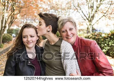 Stock Photograph - Portrait of a mother with her two young adult daughters in an affectionate pose; New Westminster, British Columbia, Canada. Fotosearch