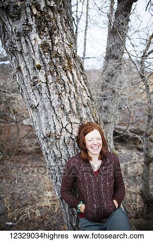 Portrait of a woman with red hair leaning on a tree and laughing with eyes closed; Homer, Alaska, United States of America View Large Photo Image Stock Photograph - Portrait of a woman with red hair leaning on a tree and laughing with eyes closed; Homer, Alaska, United States of America. Fotosearch