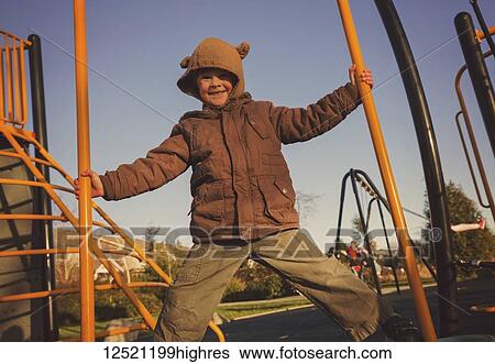 Stock Photograph - Portrait of a young boy playing on playground equipment; Langley, British Columbia, Canada. Fotosearch