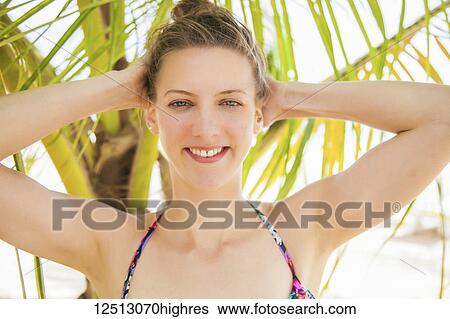 Stock Photograph - Portrait of a young caucasian woman in a bikini top with a tropical tree in the background; Negril, Jamaica. Fotosearch