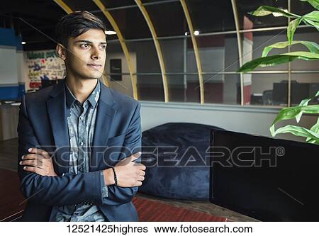 Stock Photograph - Portrait of a young millennial businessman in the workplace; Sherwood Park, Alberta, Canada. Fotosearch