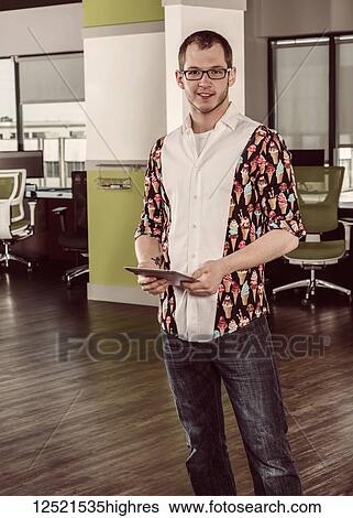 Stock Photograph - Portrait of a young millennial professional business man using technology in the workplace; Sherwood Park, Alberta, Canada. Fotosearch