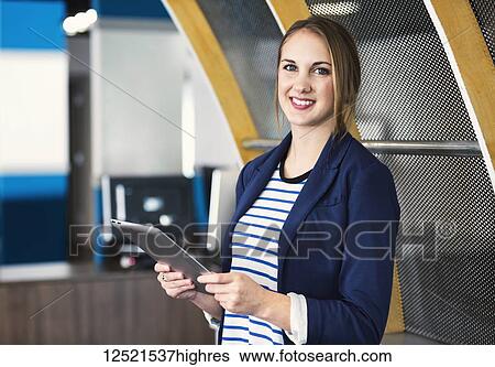 Stock Photograph - Portrait of a young millennial professional businesswoman using technology in the workplace; Sherwood Park, Alberta, Canada. Fotosearch