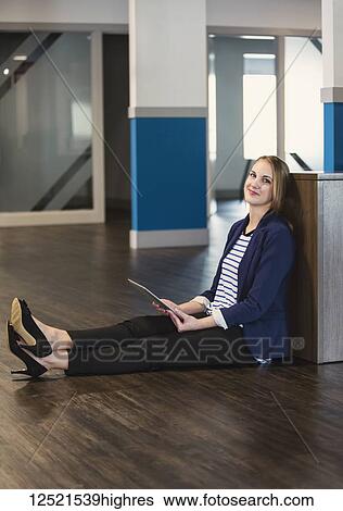 Portrait of a young millennial professional businesswoman using technology in the workplace while sitting on the floor; Sherwood Park, Alberta, Canada View Large Photo Image Stock Photograph - Portrait of a young millennial professional businesswoman using technology in the workplace while sitting on the floor; Sherwood Park, Alberta, Canada. Fotosearch