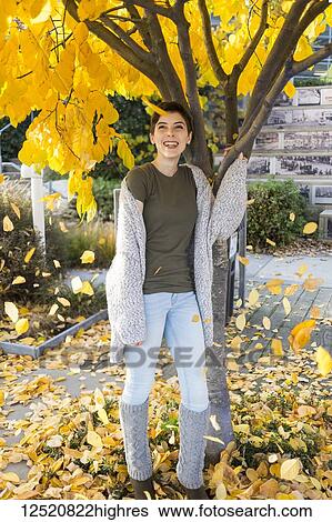 Portrait of a young woman standing under a tree with falling golden leaves in autumn; New Westminster, British Columbia, Canada View Large Photo Image Stock Photograph - Portrait of a young woman standing under a tree with falling golden leaves in autumn; New Westminster, British Columbia, Canada. Fotosearch