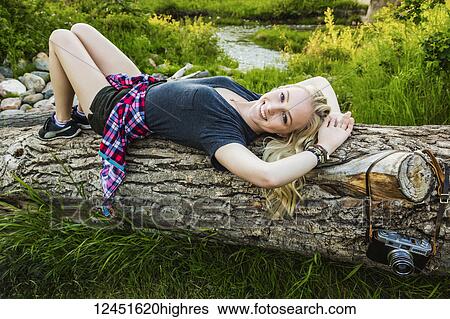 Portrait of a young woman with long blond hair laying on a log in a park; Edmonton, Alberta, Canada View Large Photo Image Stock Photograph - Portrait of a young woman with long blond hair laying on a log in a park; Edmonton, Alberta, Canada. Fotosearch