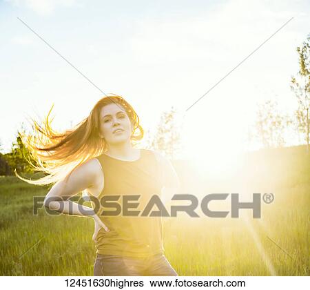 Portrait of a young woman with long hair blowing behind her and a sun flare glowing beside her; Edmonton, Alberta, Canada View Large Photo Image Stock Photograph - Portrait of a young woman with long hair blowing behind her and a sun flare glowing beside her; Edmonton, Alberta, Canada. Fotosearch