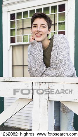 Portrait of a young woman with short brunette hair smiling and leaning on a railing View Large Photo Image Stock Photograph - Portrait of a young woman with short brunette hair smiling and leaning on a railing. Fotosearch
