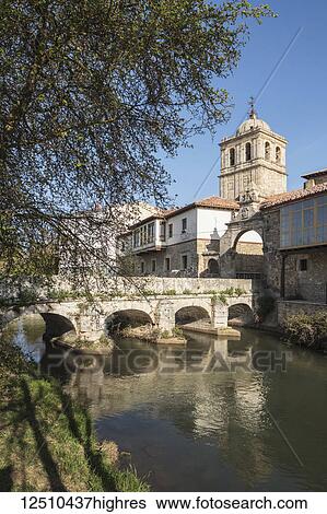 Stock Photograph - Puente del Portazgo, Puerta del Portazgo with 14th century Colegiata de San Miguel in background; Aguilar de Campoo, Palencia; Spain. Fotosearch