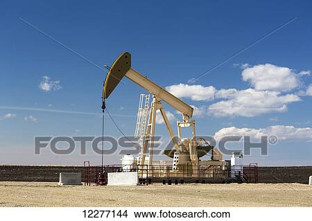 Picture - Pumpjack with blue sky and cumulus clouds; Alberta, Canada. Fotosearch