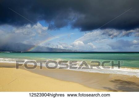 Stock Photograph - Rainbow over ocean and Baldwin Beach, on the North shore of Maui; Paia, Maui, Hawaii, United States of America. Fotosearch