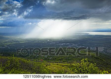 Rays of sunlight break through the dark clouds to the city below; Eagle River, Alaska, United States of America View Large Photo Image Stock Photograph - Rays of sunlight break through the dark clouds to the city below; Eagle River, Alaska, United States of America. Fotosearch
