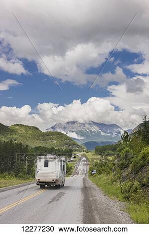 Stock Image - Recreational vehicle driving up the Alaska Highway, west of Fort Nelson, British Columba, Canada, Summer. Fotosearch
