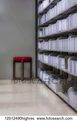 Stock Photograph - Red stool next to documents in a library; Connecticut, United States of America. Fotosearch