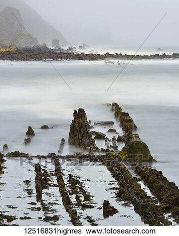 Stock Photograph - Rock formations in a shroud of mist along the coast of the North Sea; Burnmouth, Scottish Borders, Scotland. Fotosearch