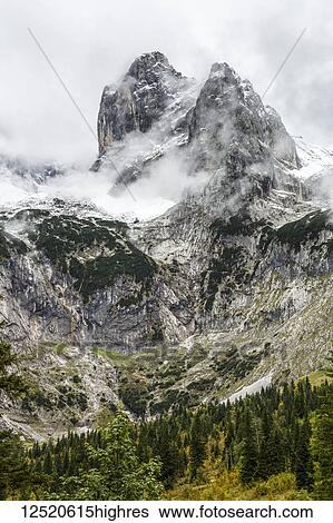 Rugged mountain peak and valley with peak coming through cloud covering and snow; Grainau, Bavaria, Germany View Large Photo Image Stock Photograph - Rugged mountain peak and valley with peak coming through cloud covering and snow; Grainau, Bavaria, Germany. Fotosearch