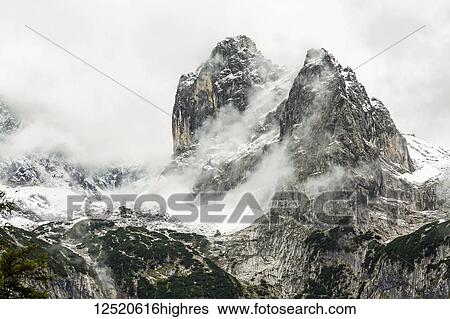 Rugged mountain peak with peak coming through cloud covering and snow; Grainau, Bavaria, Germany View Large Photo Image Stock Photograph - Rugged mountain peak with peak coming through cloud covering and snow; Grainau, Bavaria, Germany. Fotosearch