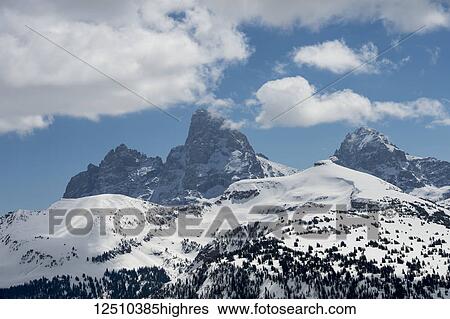 Stock Photograph - Rugged mountain peaks on a landscape covered in snow with blue sky and cloud, Peace Park; Wyoming, United States of America. Fotosearch