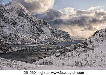 Stock Photograph - Rugged, snow-covered mountains along the coastline of Norway; Nordland, Norway. Fotosearch