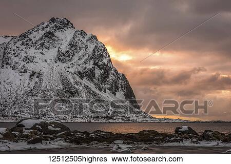 Rugged, snow-covered mountains with glowing pink clouds at sunset along the coastline of Norway; Nordland, Norway View Large Photo Image Stock Photograph - Rugged, snow-covered mountains with glowing pink clouds at sunset along the coastline of Norway; Nordland, Norway. Fotosearch