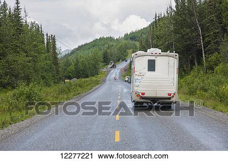 Stock Image - RV camper drives down the Alaska Highway, west of Fort Nelson, British Columbia Canada, Summer. Fotosearch