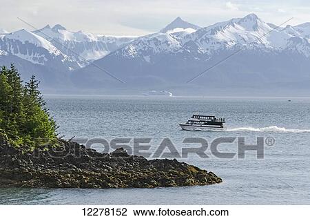 Stock Image - Scenic view of Lynn Canal and the Chilkat Mountains with a tour boat in the foreground, Southeast Alaska. Fotosearch