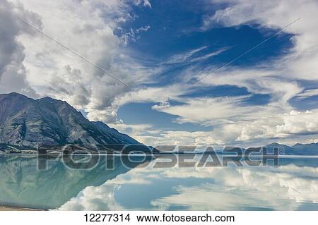 Scenic view of mountains and clouds reflecting in the calm waters of Kluane Lake, Yukon Territory, Canada, Summer View Large Photo Image Picture - Scenic view of mountains and clouds reflecting in the calm waters of Kluane Lake, Yukon Territory, Canada, Summer. Fotosearch