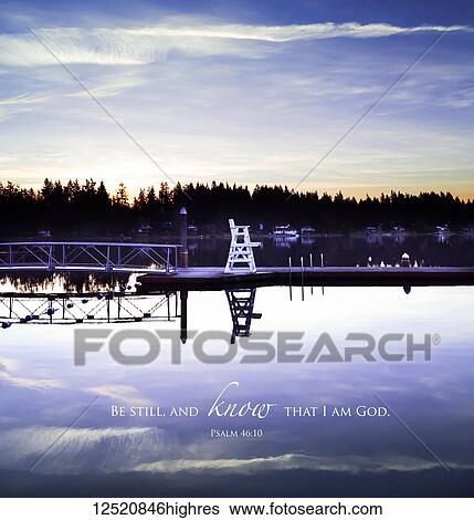 Stock Photograph - Scripture from Psalm 46: 10 on a tranquil lake with a dock at sunset; Whidby Island, Washington, United States of America. Fotosearch