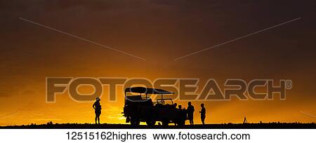 Silhouette of tourists on a luxury safari standing beside a recreational vehicle in the desert at sunset; Sossusvlei, Hardap Region, Namibia View Large Photo Image Stock Photograph - Silhouette of tourists on a luxury safari standing beside a recreational vehicle in the desert at sunset; Sossusvlei, Hardap Region, Namibia. Fotosearch