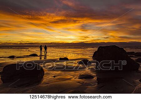 Silhouette of two people standing on Wreck Beach with an orange glow at sunset; Vancouver, British Columbia, Canada View Large Photo Image Stock Photograph - Silhouette of two people standing on Wreck Beach with an orange glow at sunset; Vancouver, British Columbia, Canada. Fotosearch