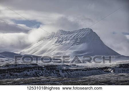 Stock Photograph - Snow covered peak behind the town of Djupavik; Djupavik, West Fjords, Iceland. Fotosearch