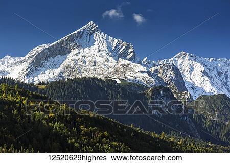 Stock Photograph - Snow-covered rugged mountain range with blue sky; Garmisch-Partenkirchen, Bavaria, Germany. Fotosearch