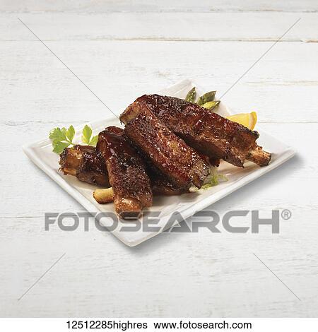 Stock Photograph - Spare ribs served on a white plate. Fotosearch