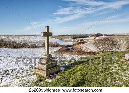 Stock Photograph - Stone cross in the graveyard of Branxton Church with a light covering of snow on the ground; Flodden, England. Fotosearch