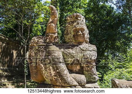 Stock Photograph - Stone figures on the causeway to the Victory Gate tower (Gopuram); Angkor Thom, Siem Reap, Cambodia. Fotosearch
