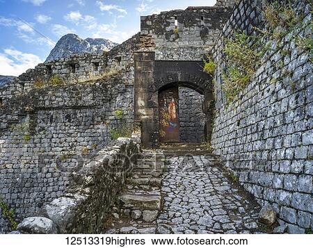 Stock Photograph - Stone walls and path of the Kotor Fortress with mountain peak and blue sky; Kotor, Monte. Fotosearch