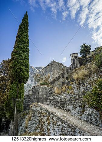 Stock Photograph - Stone walls and path of the Kotor Fortress with mountain and blue sky; Kotor, Monte. Fotosearch