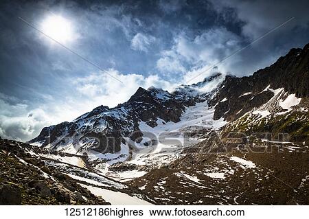 Stock Photograph - Storm clouds over Aiguille des Glaciers (mountain) and Estellette Glacier and moraine, Alps; Aosta Valley, Italy. Fotosearch
