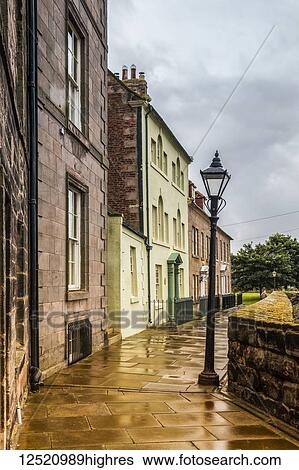 Stock Photograph - Street of Georgian houses and lamp post with rain soaked paving; Berwick Upon Tweed, England. Fotosearch