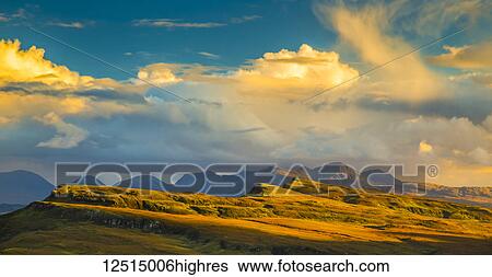 Stock Photograph - Sunlight illuminating the mountainous landscape and clouds; Isle of Skye, Scotland. Fotosearch