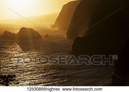 Stock Photograph - Sunrise over Paoakulani Isle, Moku Puka Isle and Pa'alaea Islands seabird sanctuaries, Pololu Valley Lookout, North Kohala, Hamakua Coast. This area is only accessible by boat; Island of Hawaii, Hawaii, United States of America. Fotosearch