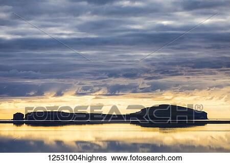 Stock Photograph - Sunset over an island near Hofsos, North Iceland; Hofsos, Iceland. Fotosearch