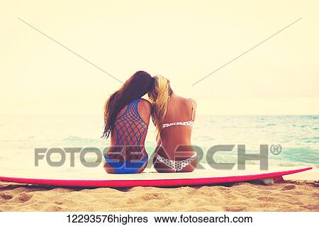 Stock Photograph - Surfer Girls On The Beach At Sunset. Summer Outdoor Lifestyle. Best Friends Hanging Out On The Beach.. Fotosearch