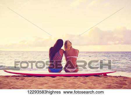 Surfer Girls On The Beach At Sunset. Summer Outdoor Lifestyle. Best Friends Hanging Out On The Beach. View Large Photo Image Stock Photograph - Surfer Girls On The Beach At Sunset. Summer Outdoor Lifestyle. Best Friends Hanging Out On The Beach.. Fotosearch