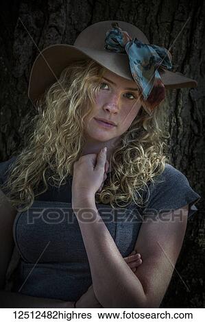 Teenage girl with blond, curly hair wearing a brimmed hat with scarf, standing in front of a tree; Connecticut, United States of America View Large Photo Image Stock Photograph - Teenage girl with blond, curly hair wearing a brimmed hat with scarf, standing in front of a tree; Connecticut, United States of America. Fotosearch