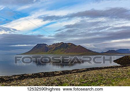 Stock Photograph - The colourful volcanic hills reflect onto the ocean at sunset in Western Iceland; Iceland. Fotosearch