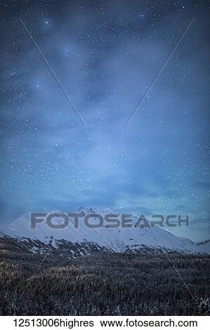 Stock Photograph - The faint glow of Aurora Borealis in the night sky illuminates the sparse cloud over Moose Pass, Kenai Peninsula, South-central Alaska; Moose Pass, Alaska, United States of America. Fotosearch