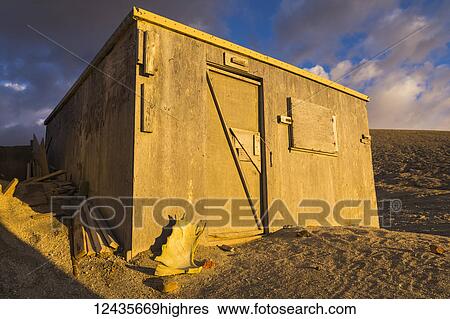 Stock Photograph - The larger of the Baked Mountain Huts is lit up at sunset in the Valley of Ten Thousand Smokes in Katmai National Park; Alaska, United States of America. Fotosearch